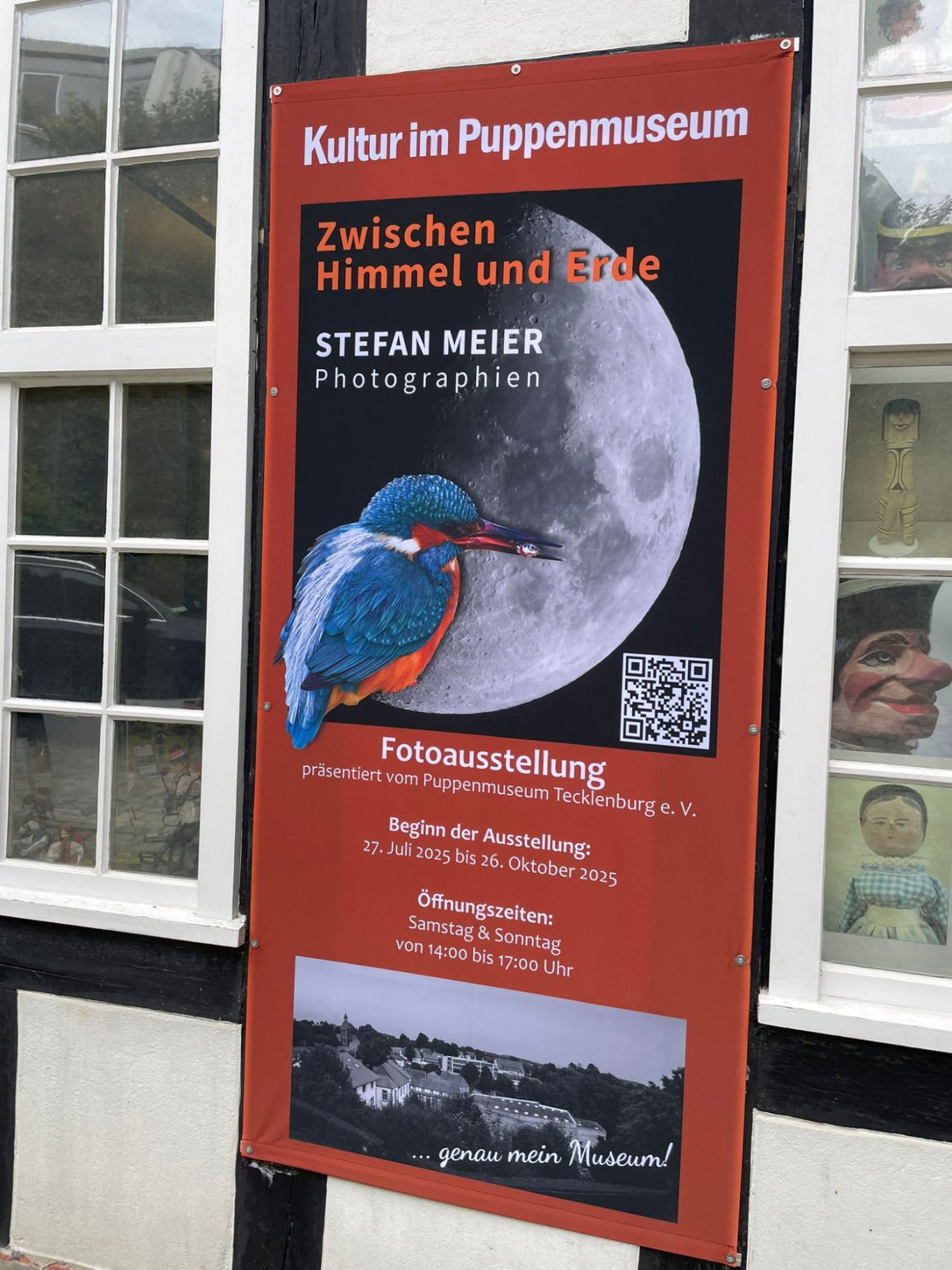 Plakat zur Fotoausstellung „Zwischen Himmel und Erde“ mit einem Eisvogel und Mond.